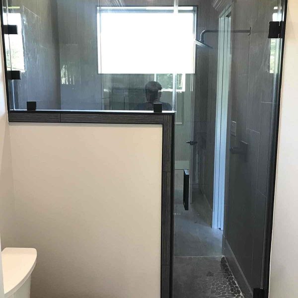 A shower area with glass door and wall